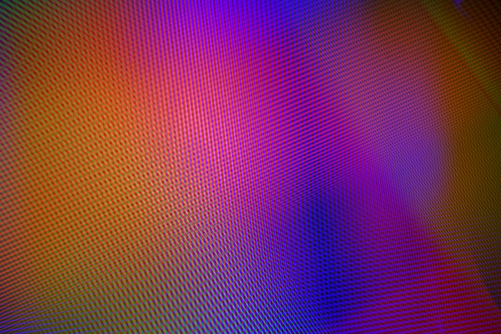 Cette image représente une noctographie en couleur de Cédric Poulain.  On y voit un entrelas de lignes parallèles colorées de différentes largeurs formant une sorte de bruit aléatoire avec un léger dégradé coloré dans les tons chauds violet orangé.